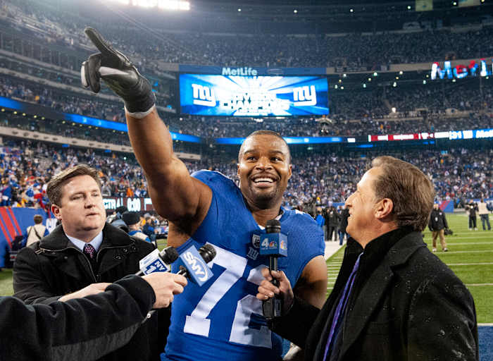 Osi Umenyiora points to the crowd while being interviewed after a Giants victory.